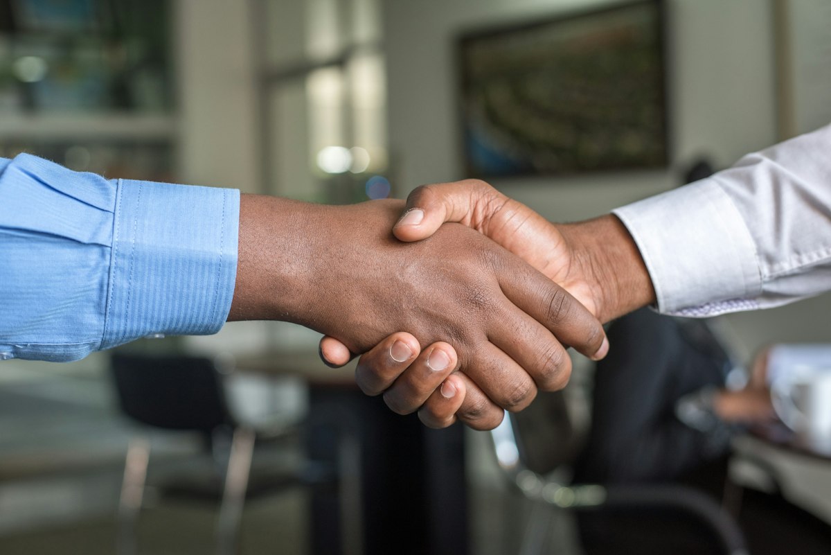 Two people shaking hands over a table