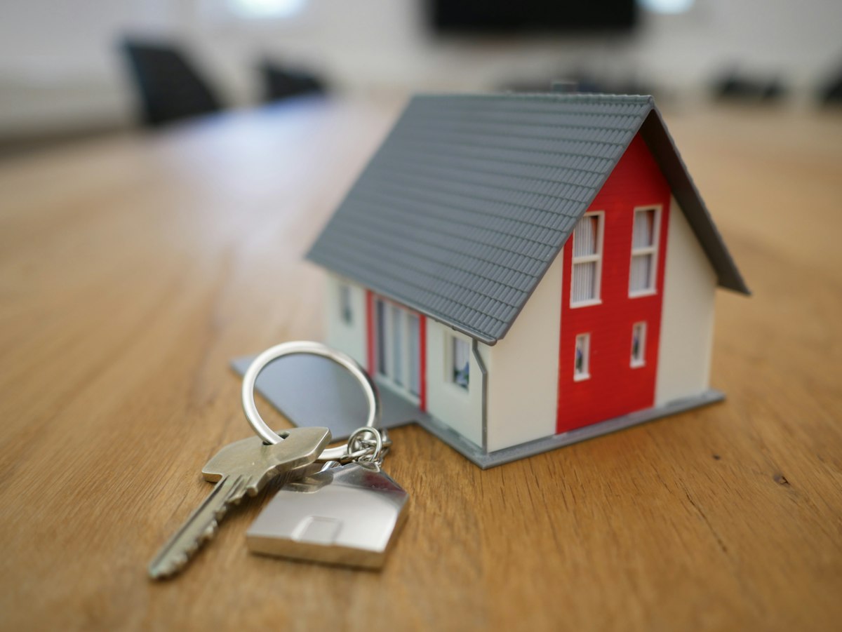 Small model house resting beside a set of keys